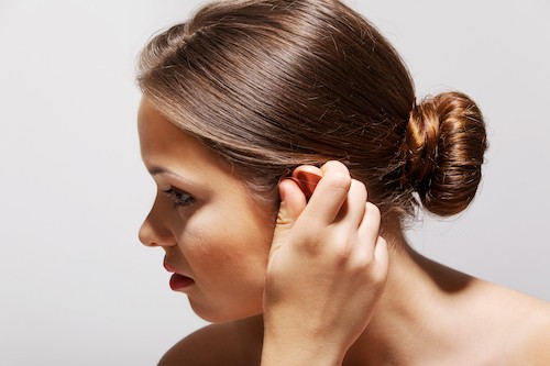 Woman Covering ear because of tinnitus